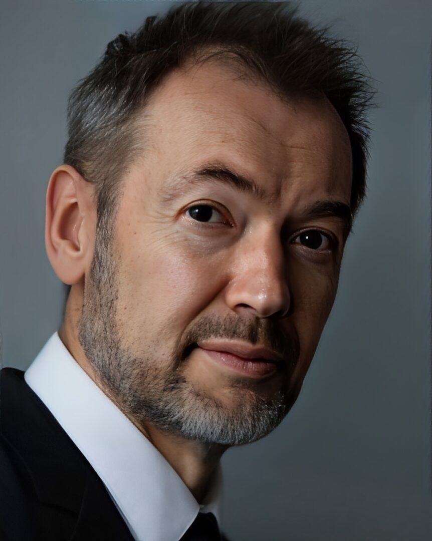 person-3 (2) (1) A man with grey hair and beard wearing a suit.